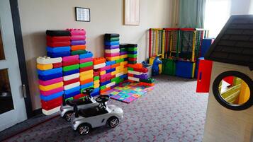 A play area with colorful building blocks, a toy car, and a playpen with a ball pit.