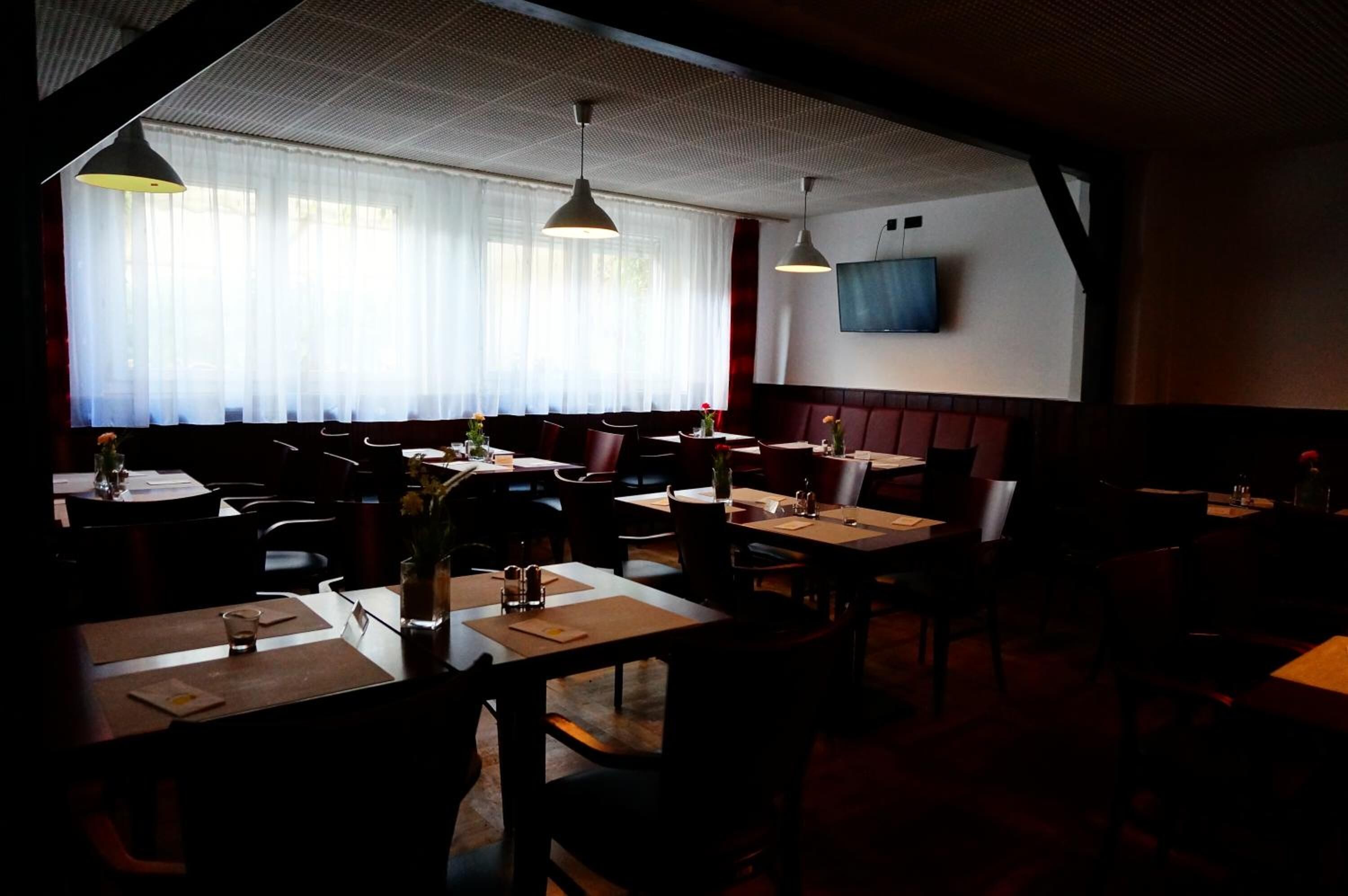 A restaurant with booths and tables, a TV mounted on the wall, and a ceiling with a textured pattern.