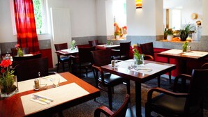 Un restaurante con varias mesas y sillas, cada conjunto con cubiertos y servilletas.