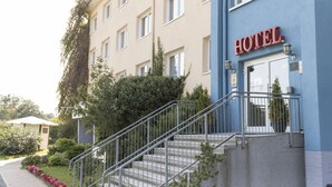 Un hotel con fachada azul, una escalera que conduce a la entrada y un cartel que dice "HOTEL".