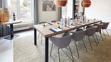 A modern conference room with a long table, grey chairs, and copper pendant lights.