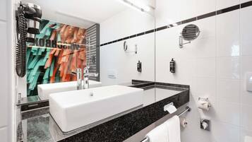Un baño moderno con un espejo grande, dos lavamanos, una ducha y un perchero para toallas.