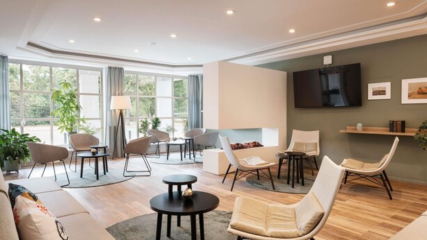 A modern living room with a sofa, chairs, a coffee table, and a TV. - ibis Styles Neckarsulm  (Neckarsulm)