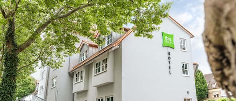 Un hôtel de deux étages avec une façade blanche, une enseigne verte indiquant « ibis styles » et une entrée abritée.