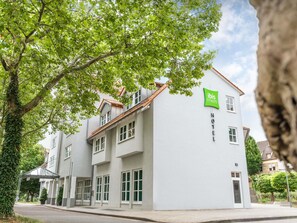 A two-story hotel with a white facade, a green sign indicating 'ibis styles,' and a covered entrance. - ibis Styles Neckarsulm  (Neckarsulm)