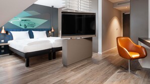A modern hotel room with a bed, a TV, a desk, and a chair. - ibis Styles Neckarsulm  (Neckarsulm)