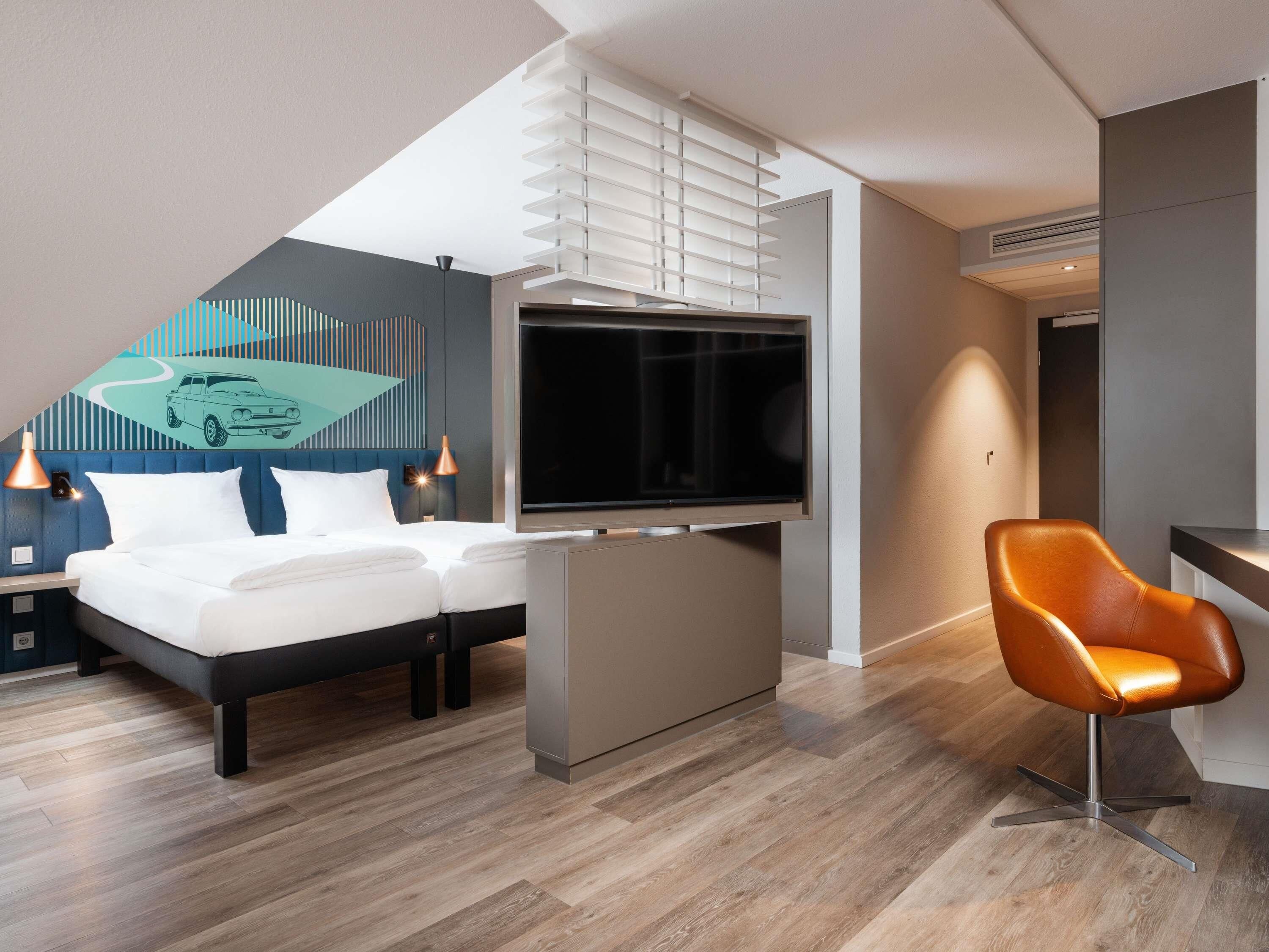 Een moderne hotelkamer met een bed, een televisie, een bureau en een stoel.