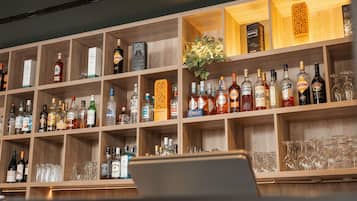 Zona de bar con estantes llenos de botellas de licores y vasos.