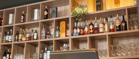 A bar area with shelves stocked with various liquor bottles and glasses.