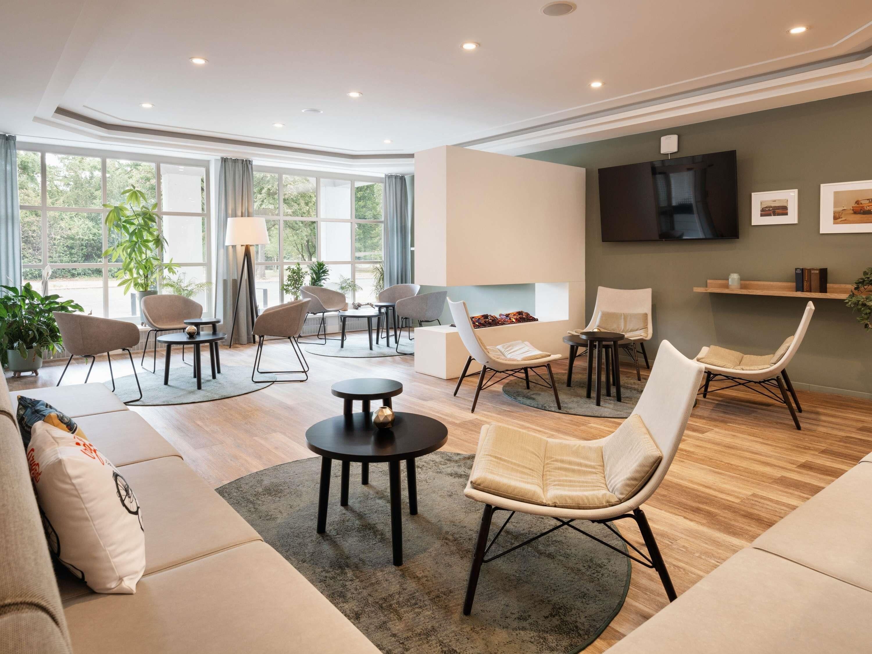 Een moderne woonkamer met een bank, fauteuils, een salontafel en een televisie.