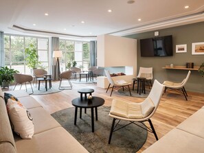 A modern living room with a sofa, chairs, a coffee table, and a TV. - ibis Styles Neckarsulm  (Neckarsulm)