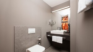 A modern bathroom with a toilet, sink, and mirror. - ibis Styles Neckarsulm  (Neckarsulm)