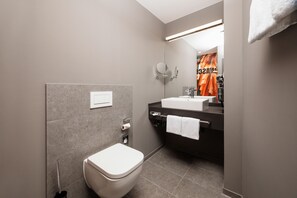 A modern bathroom with a toilet, sink, and mirror. - ibis Styles Neckarsulm  (Neckarsulm)