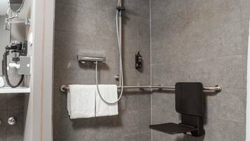 A shower with a handheld showerhead, a towel rack, and a soap dispenser.