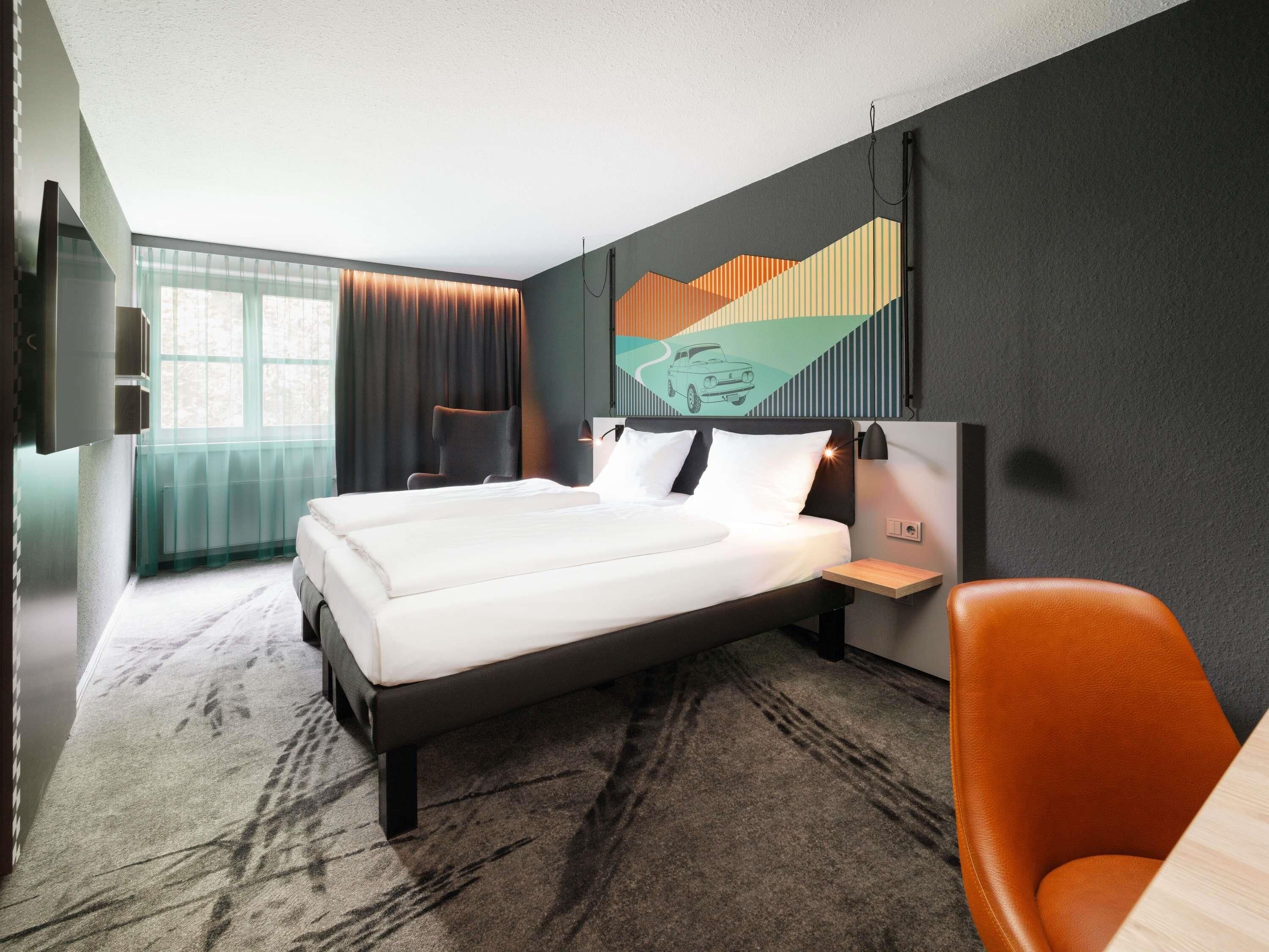 Habitación de hotel con una cama grande, una silla, un escritorio y una ventana con cortinas.