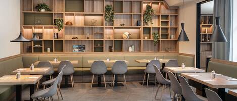 Un restaurante moderno con estantes de madera, asientos verdes e iluminación colgante.