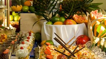 Una mesa con diversas frutas, un cuenco blanco y vasos de un postre en capas.