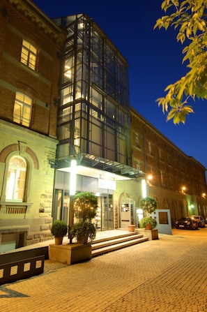 Un hotel con fachada de vidrio, exterior de ladrillo y una entrada bien iluminada.
