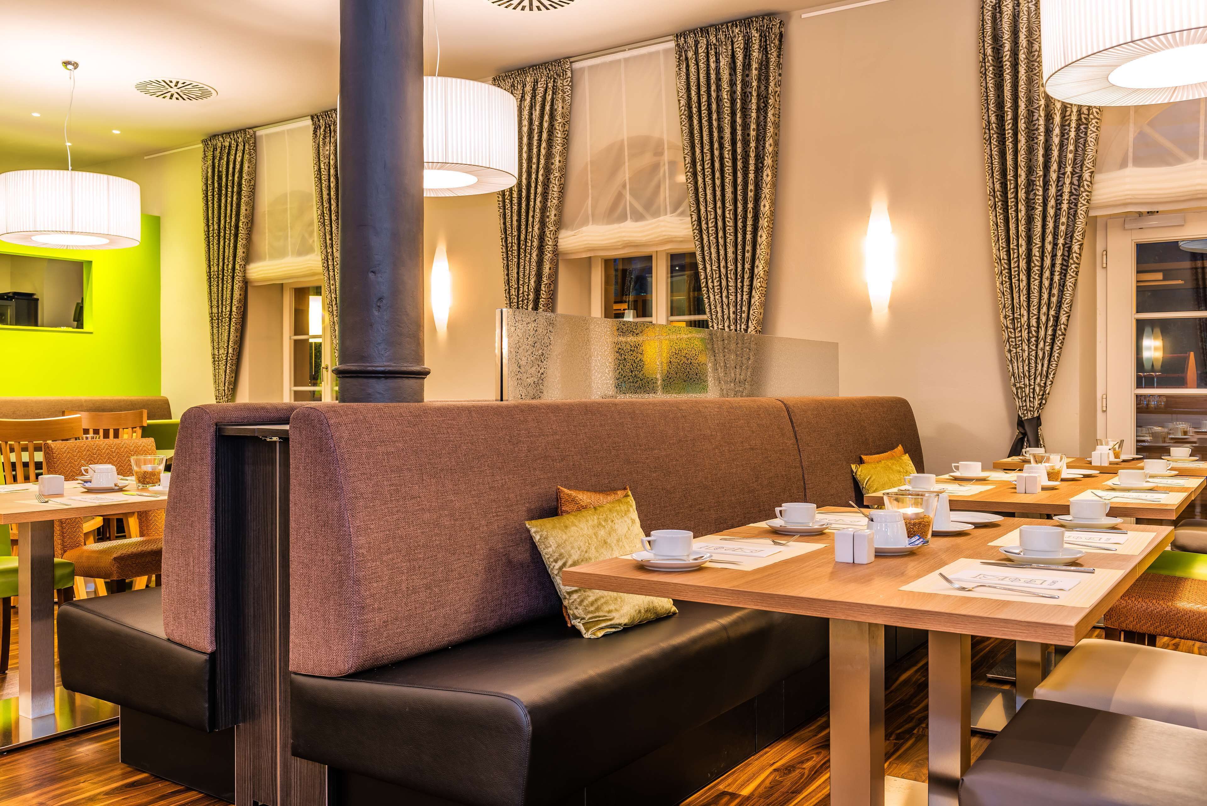 Un restaurante con una larga mesa dispuesta para comer, un banco acolchado y una pared de color verde brillante.