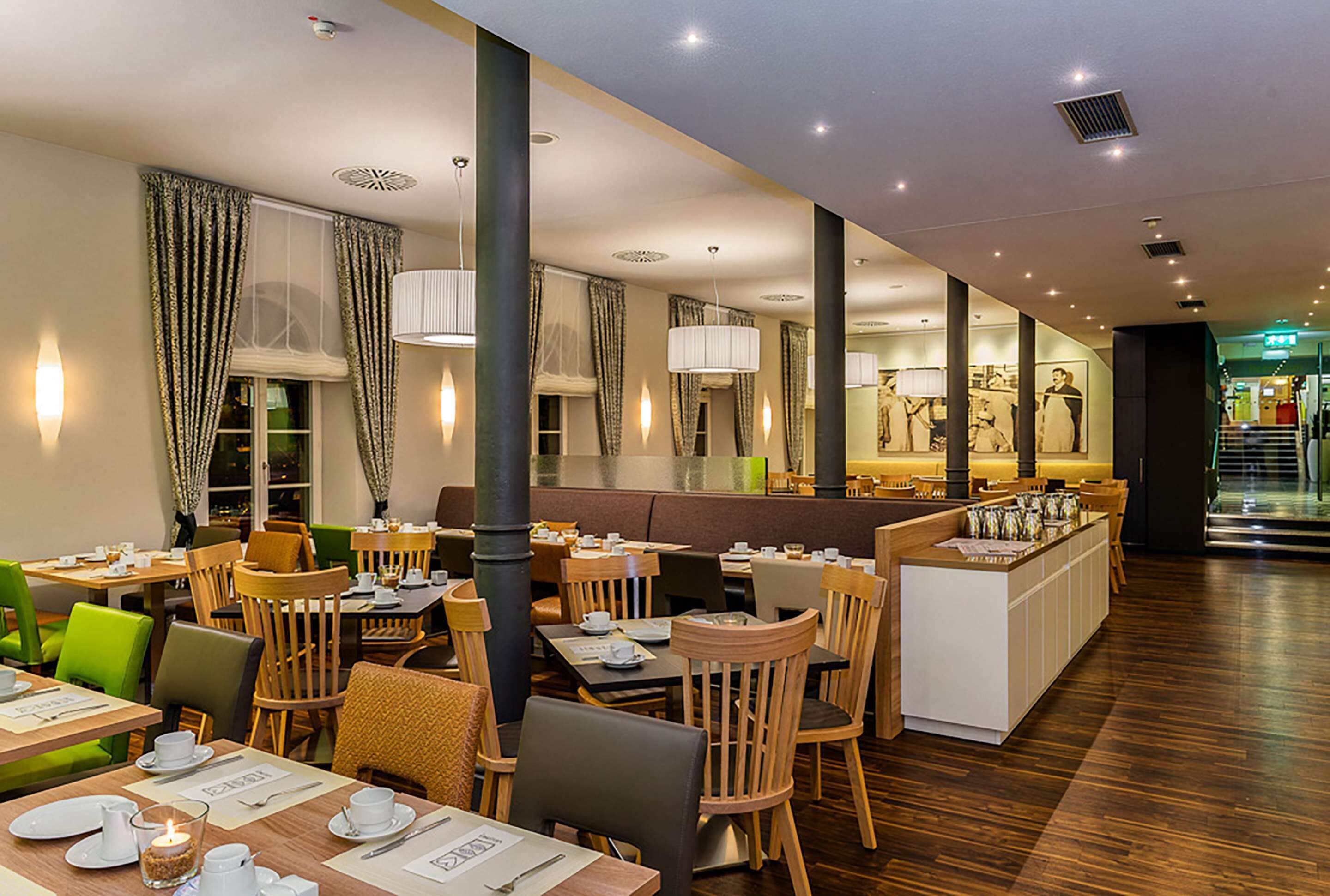Un restaurante con mesas y sillas de madera, una zona de bar y vistas a la calle.
