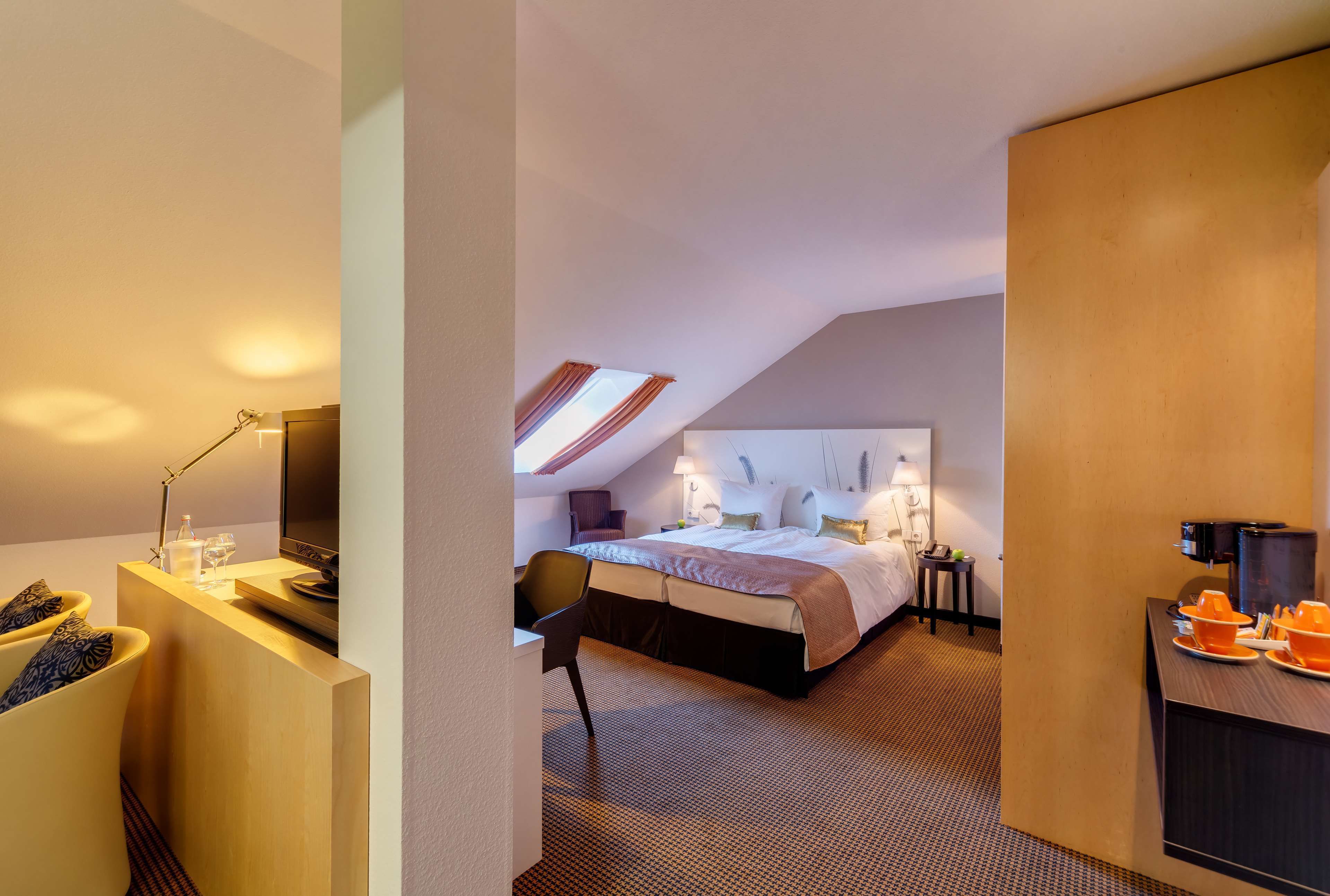 Quarto de hotel moderno com uma cama grande, uma escrivaninha e uma televisão.