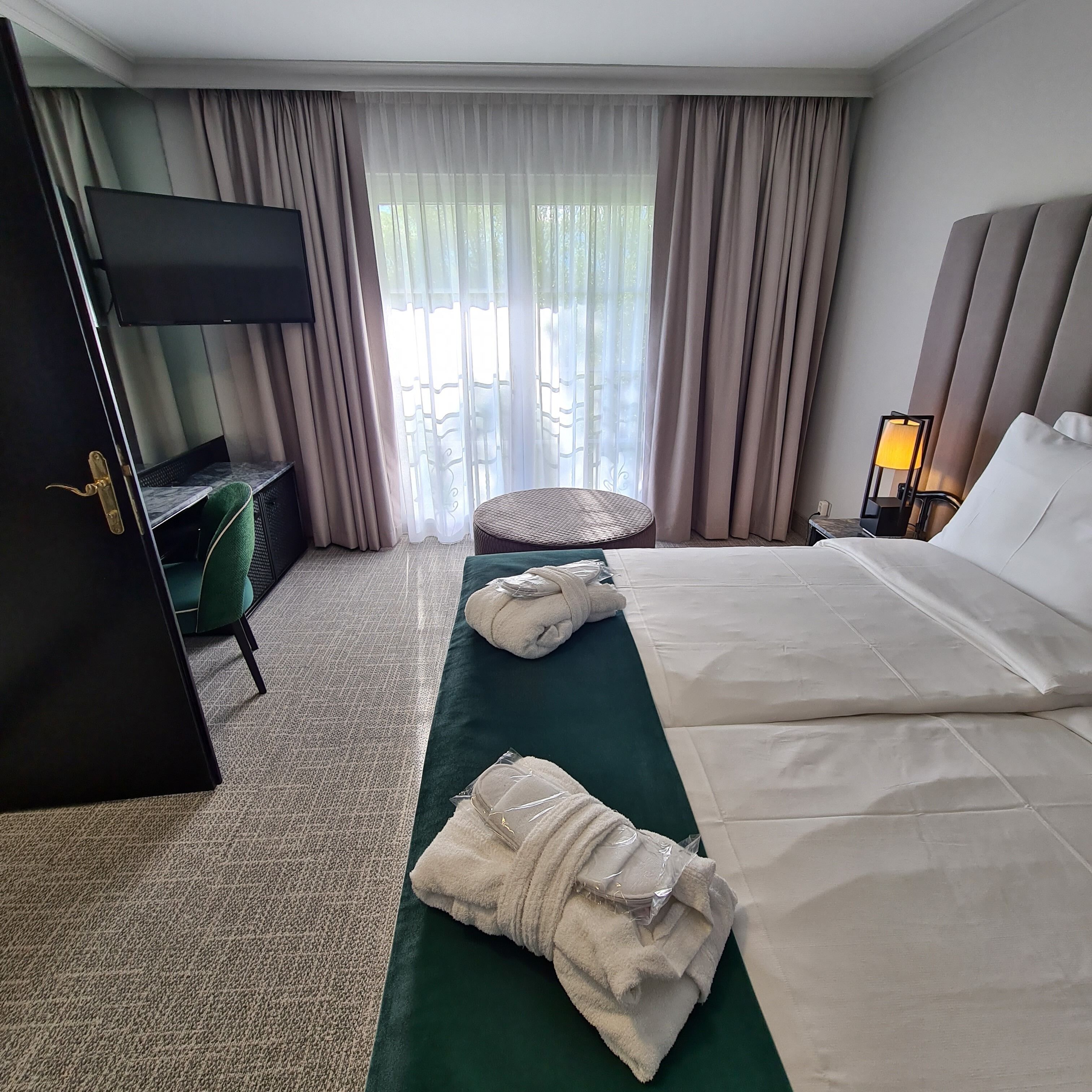 Hotelkamer met een bed, een televisie, een bureau, een stoel, een lamp en uitzicht op de omgeving.