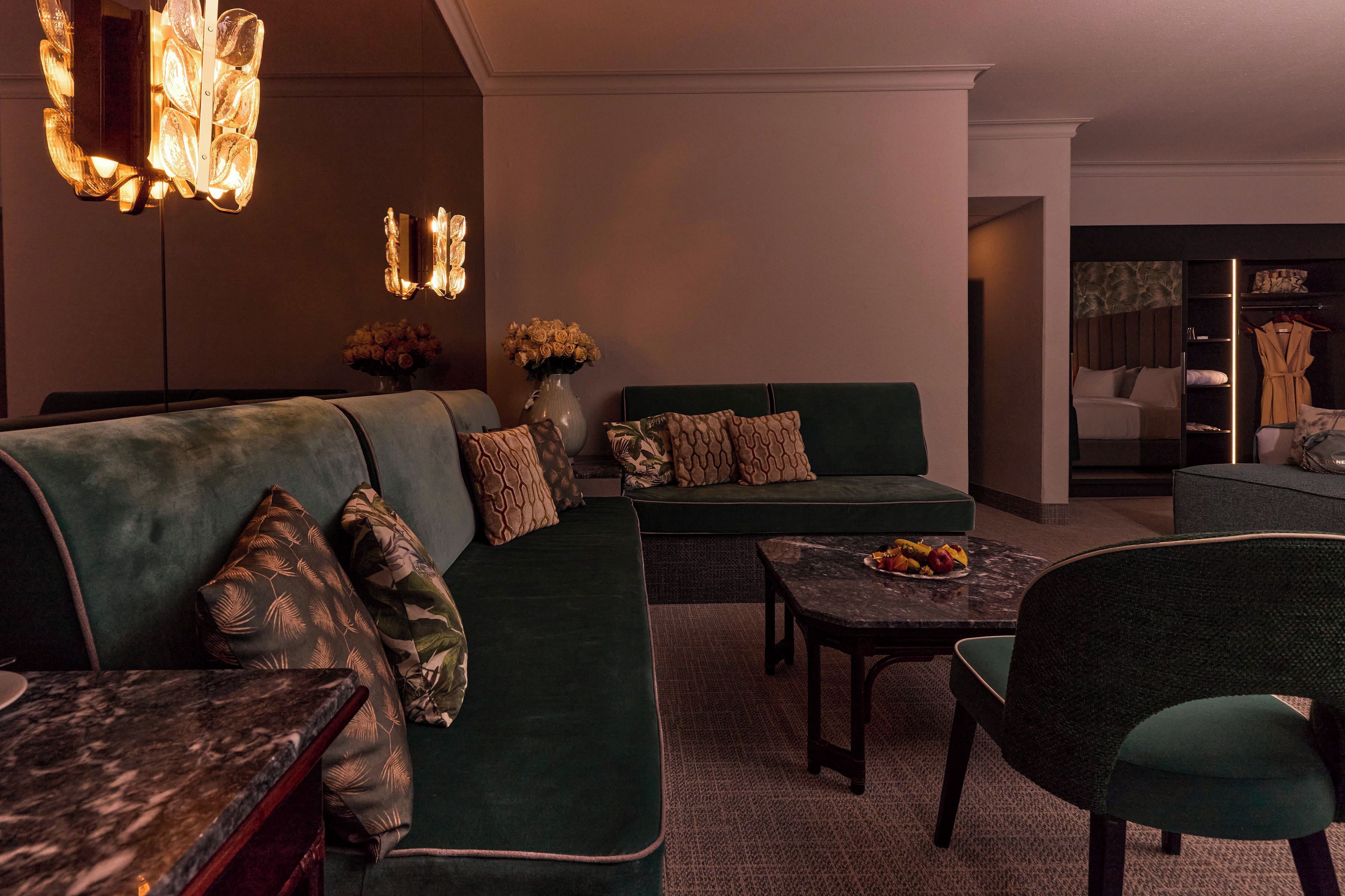 A modern lounge area with a sectional sofa, a marble coffee table, and a green armchair.