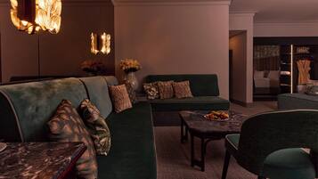 A modern lounge area with a sectional sofa, a marble coffee table, and a green armchair.