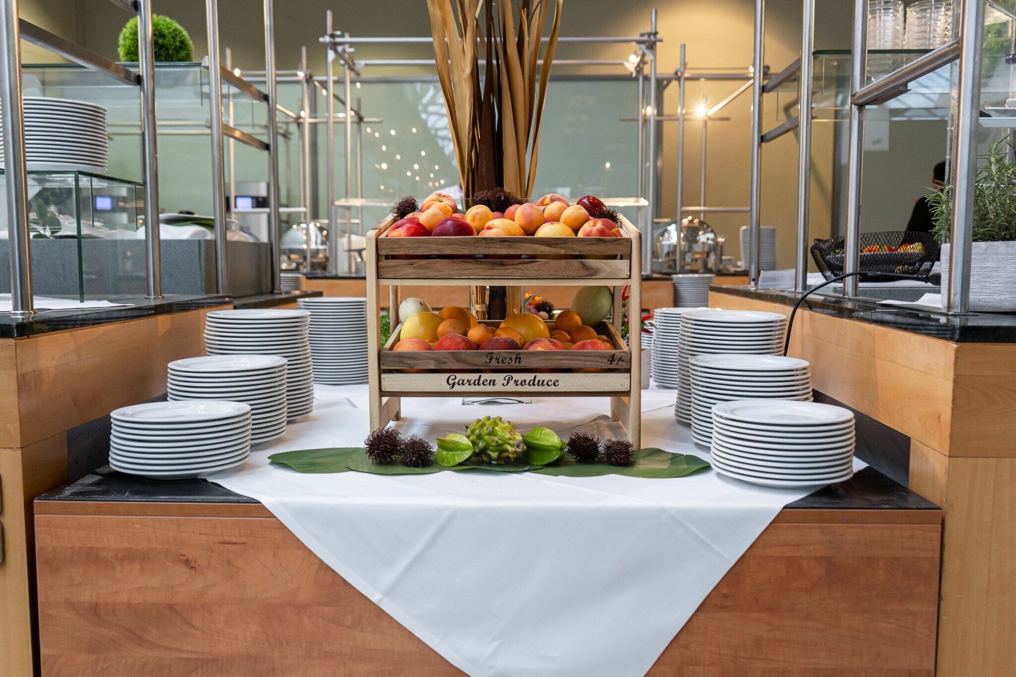 A buffet setup with fresh garden produce, plates, and a decorative centerpiece.