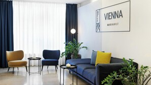 Ein modernes Wohnzimmer mit einer Couch, zwei Sesseln, einem kleinen Tisch und einem Blumentopf.