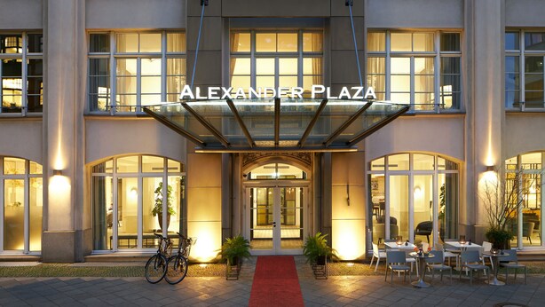 The exterior of the Alexander Plaza hotel with a red carpet leading to the entrance, large glass windows, and outdoor seating area. - Classik Hotel Alexander Plaza (Berlin)