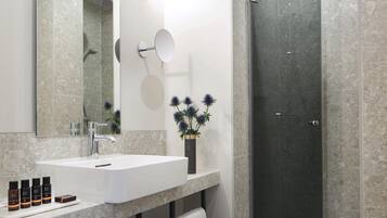 A modern bathroom with a large mirror, a sink, and a shower.