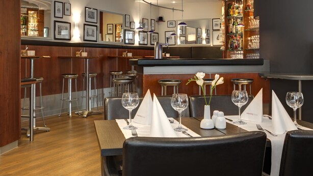 Un restaurant doté d’un bar, de tableaux encadrés aux murs et d’un comptoir bien garni de bouteilles.
