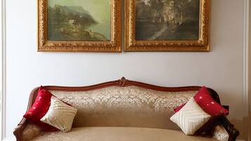 A room with a classic sofa and two framed paintings on the wall.
