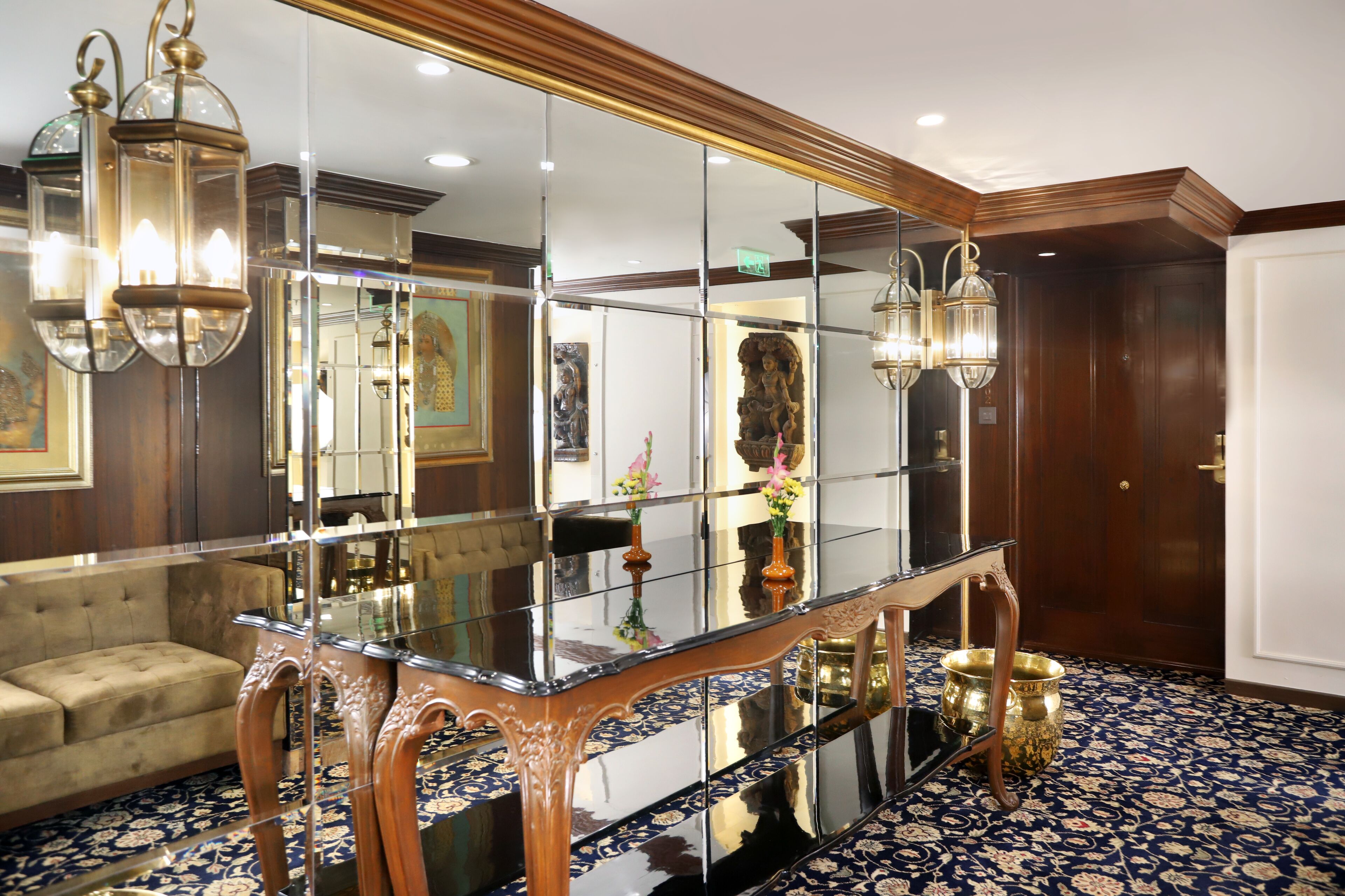 A room with a glass partition, a sofa, a wooden table, and two wall-mounted lights.