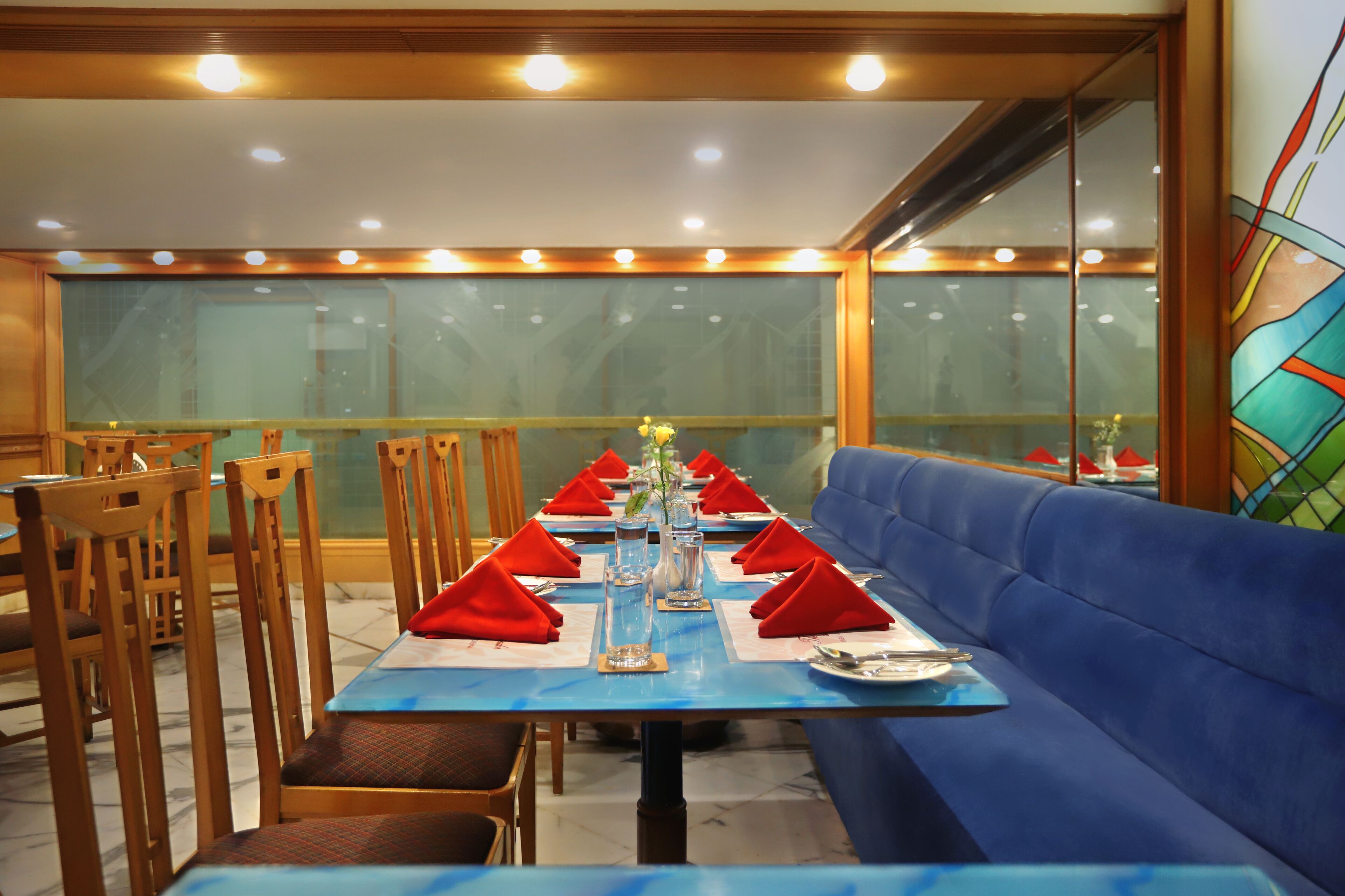 A dining area with a long table set for a meal, blue upholstered seating, and wooden chairs.