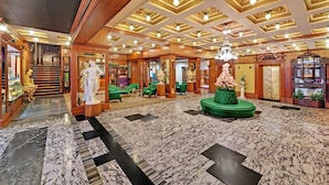 A grand lobby with a marble floor, ornate ceiling, and green seating areas. - The Ambassador, Mumbai (Mumbai)