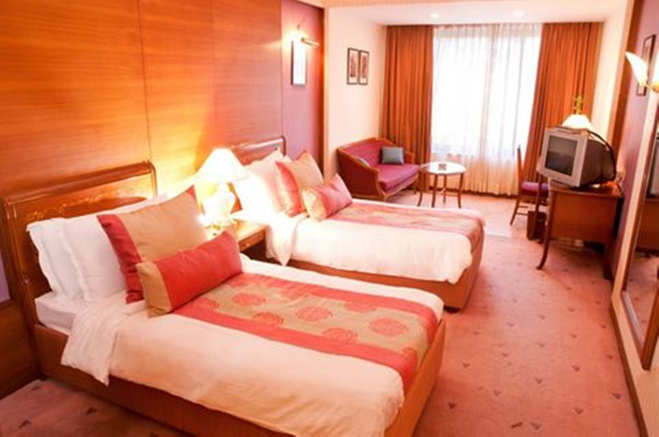 A hotel room with two beds, a sofa, a television, and a small table.