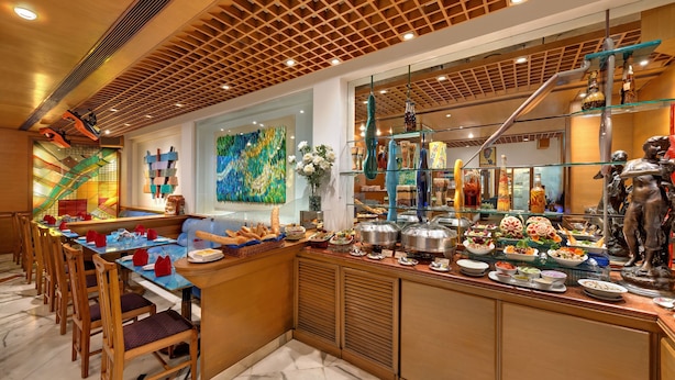 A buffet area with a variety of food items, a seating area with chairs, and a decorative ceiling. - The Ambassador, Mumbai (Mumbai)