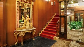 A grand entrance with a marble staircase, a large ornate mirror, and a statue on a pedestal. - The Ambassador, Mumbai (Mumbai)