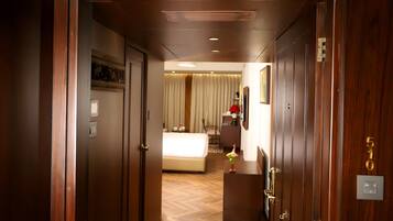 A hotel hallway with wooden doors, a bed with white bedding, a desk with a vase, and a number 510 sign.