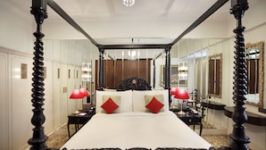 A four-poster bed with a canopy, a nightstand with a lamp, and a mirror on the wall. - The Ambassador, Mumbai (Mumbai)