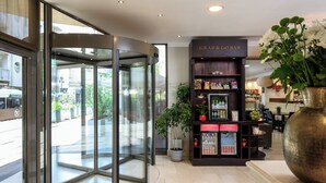 A hotel lobby with a revolving door, a 'Grab & Go Bar' kiosk, and a large potted plant. - Leonardo Hotel Budapest (Budapest)