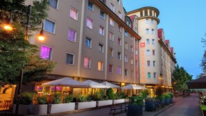 A hotel with multiple floors, outdoor seating with umbrellas, and a prominent building name. - Leonardo Hotel Budapest (Budapest)