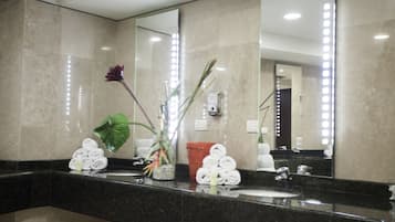 Un bagno moderno con uno specchio grande, pareti in marmo, un lavandino e una pianta in vaso.