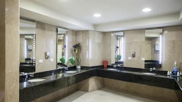 A modern bathroom with two sinks, large mirrors, and a potted plant.