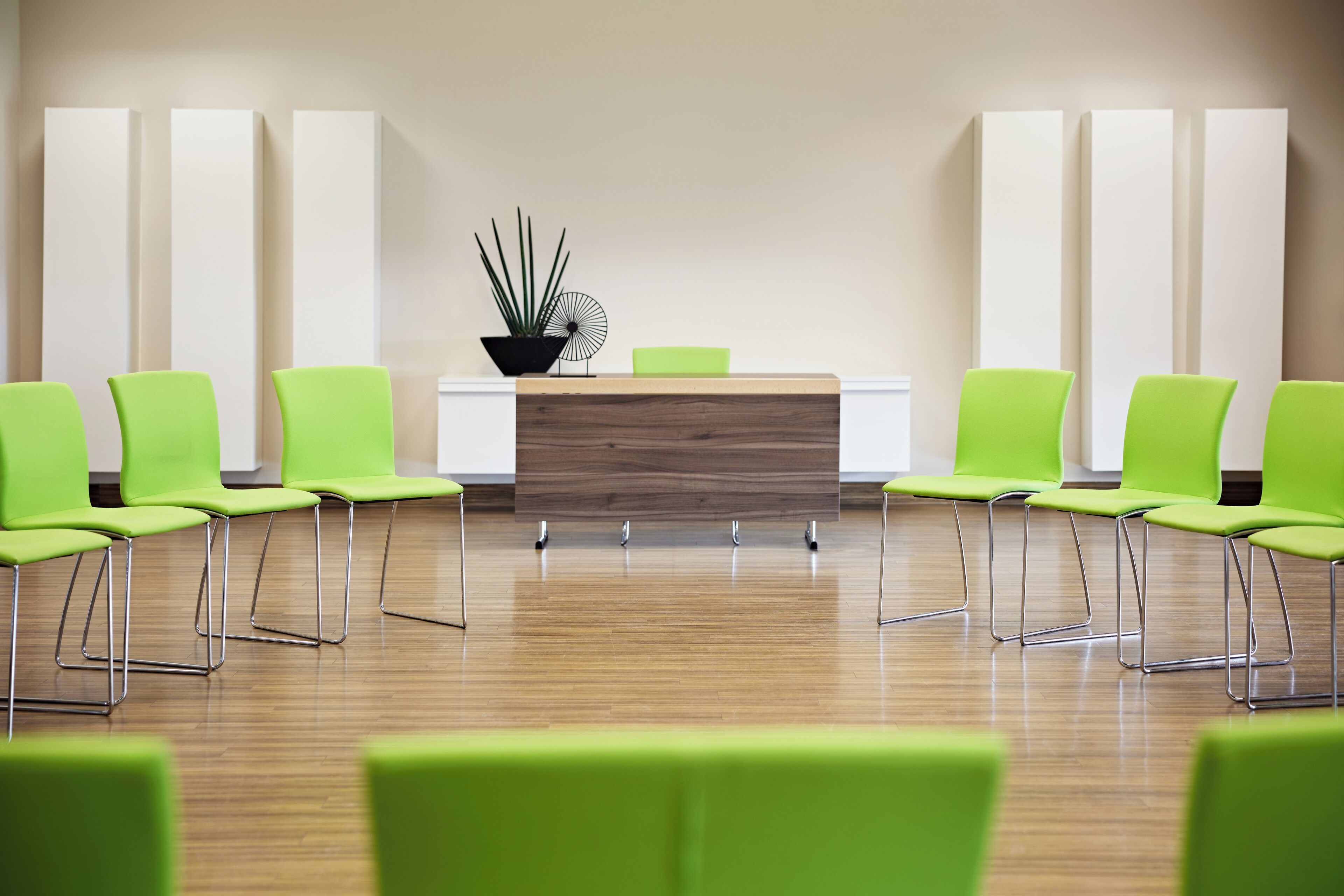 A reception area with a wooden reception desk, green chairs, and a potted plant.
