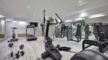 Un gimnasio moderno con cintas de correr, máquinas de pesas y pesas libres.