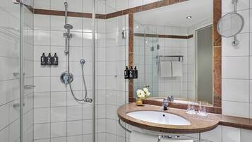 Une salle de bain moderne avec une douche à parois de verre, un lavabo sur un plan de travail en granit et un grand miroir.