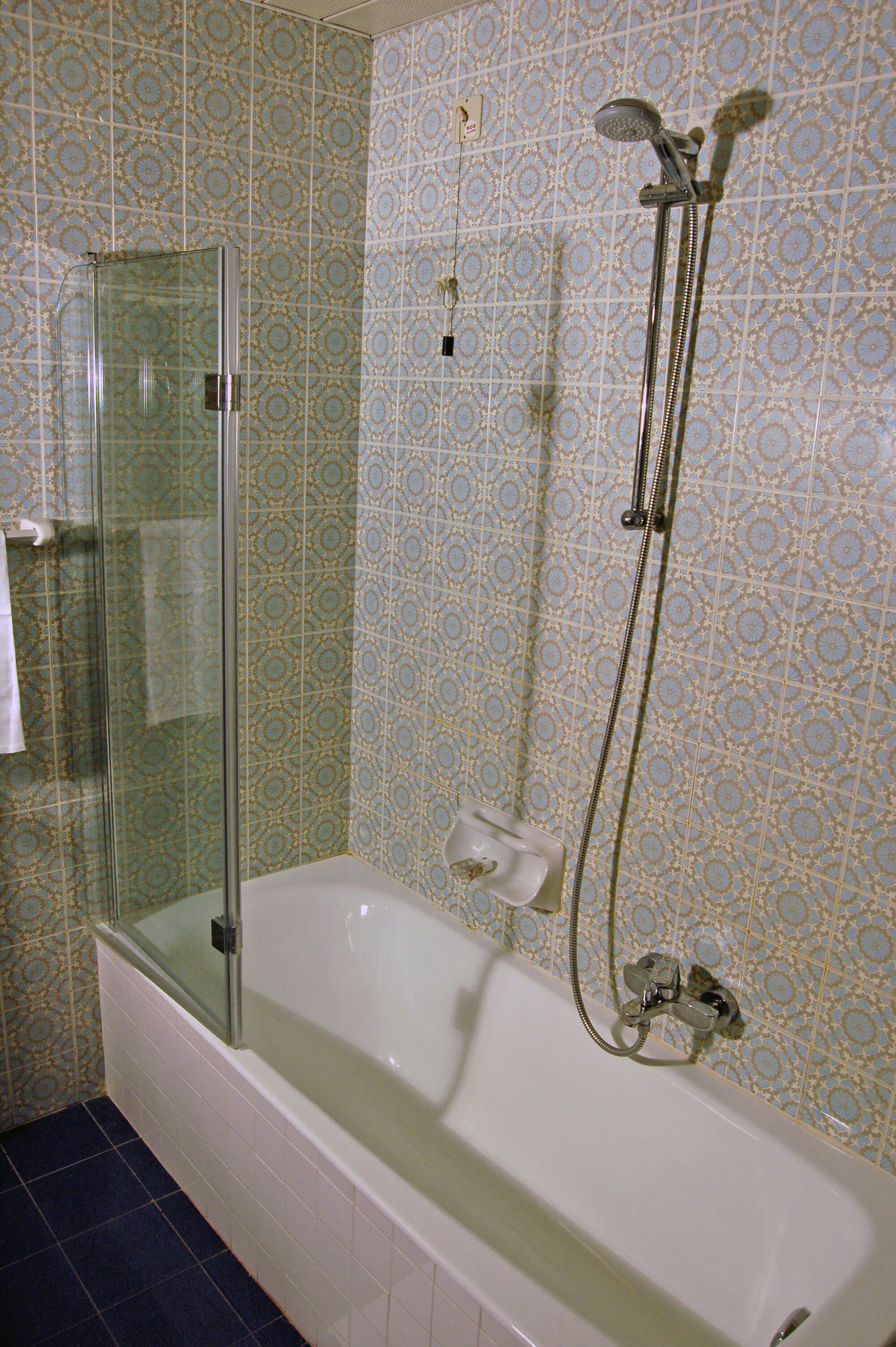 A bathroom with a glass-enclosed shower, a bathtub, and a showerhead.